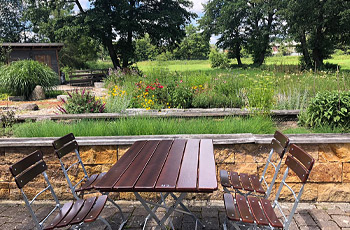 Tisch und Stühle vor Naturgarten